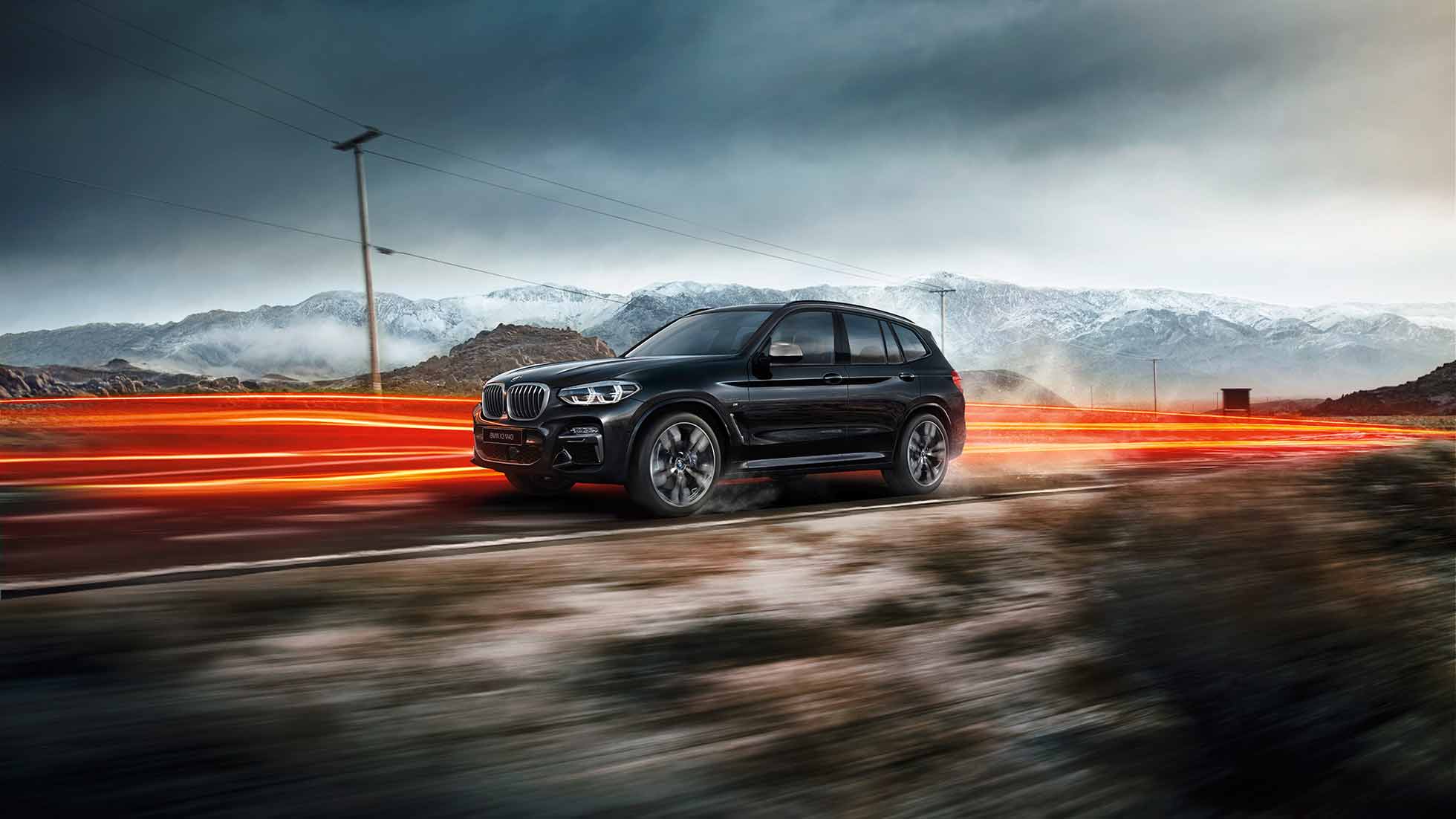 BMW X3 M40i и BMW X3 M40d, вид сбоку. BMW X3 M40i и BMW X3 M40d, Черный Сапфир металлик, в движении, внешний вид, вид сбоку на фоне горного пейзажа, полосы света.